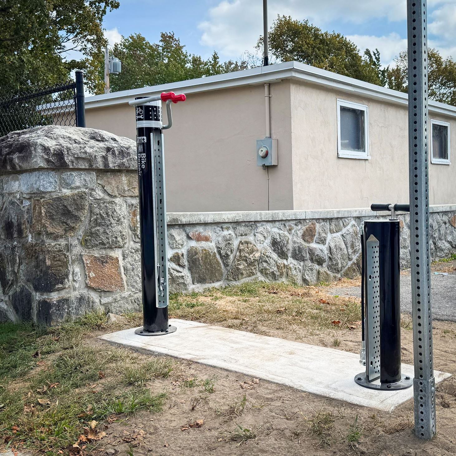 A bike repair stand and pump positioned next to a stone wall