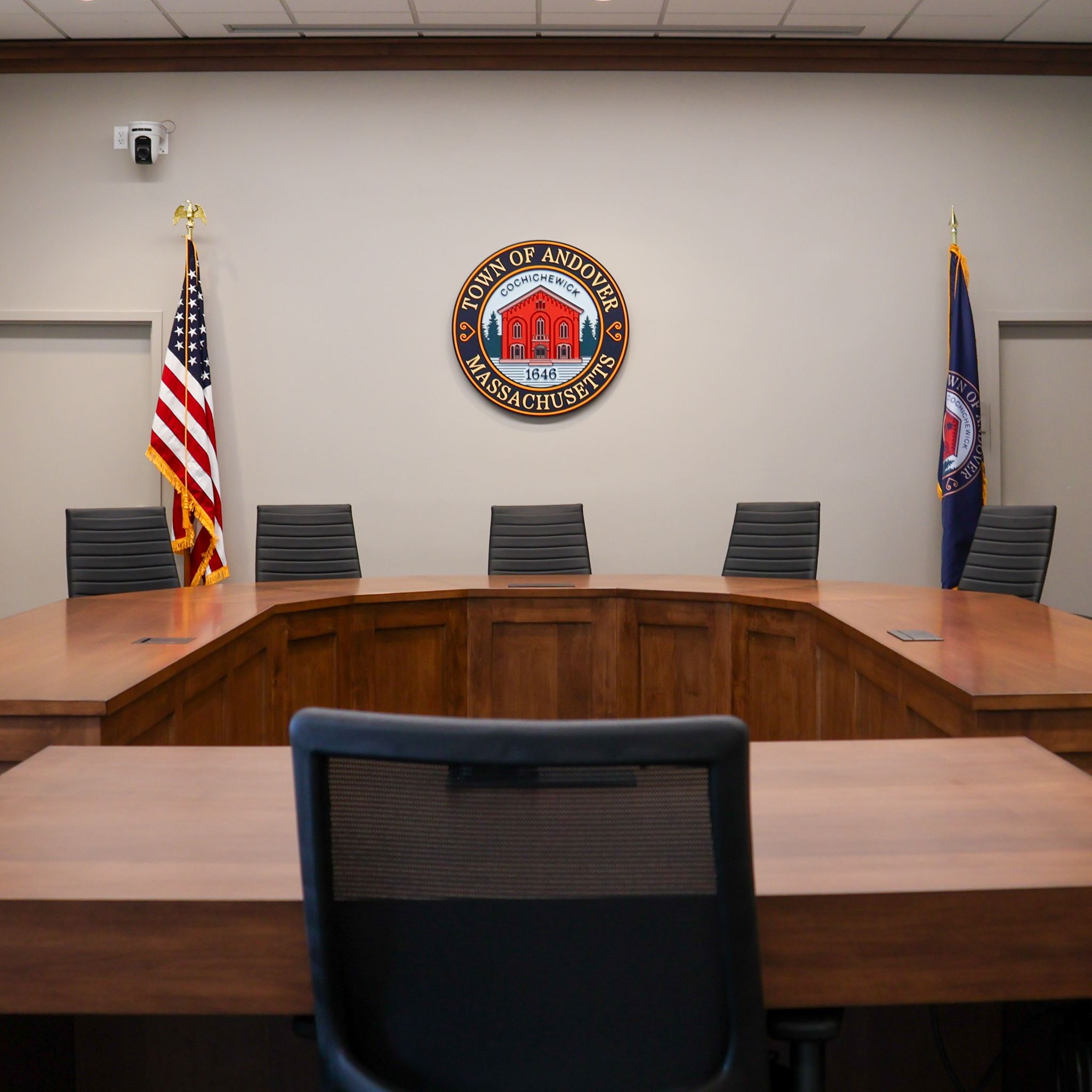 Several chairs around an ornate wood table with the Andover Town Seal on the wall in the background